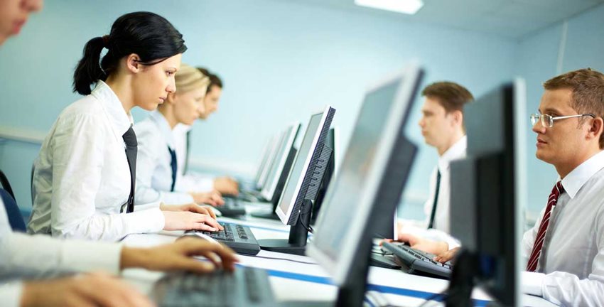 Hombres y mujeres trabajando en computadores. 