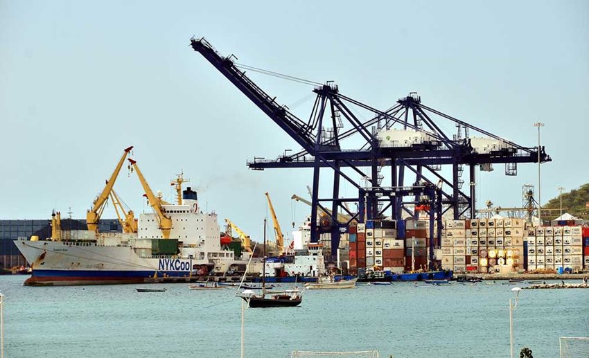 Puerto con contenedores para exportar y descargar, ubicados al lado de un barco de carga.