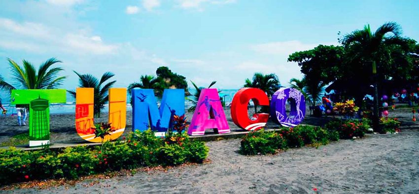 Letrero de Tumaco, de colores, en medio de una playa.