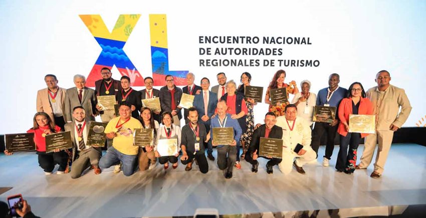 Descripción de la imagen: Hombres y mujeres en el escenario, con sus premios y medallas, posando para la foto.