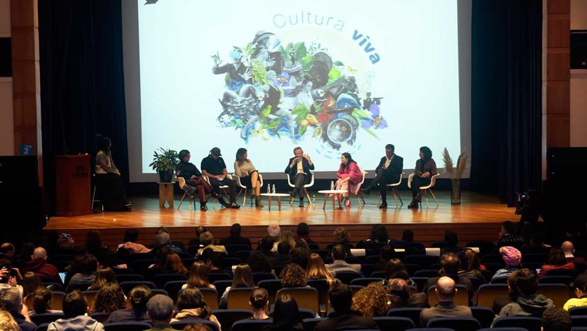 Grupo de personas en una tarima hablando ante otras sentadas en auditorio.