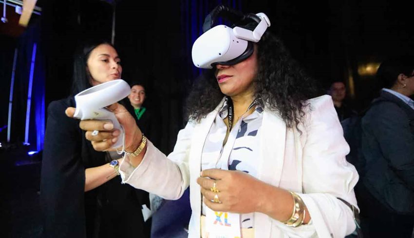 Descripción de la imagen: Mujer vestida de traje blanco, utilizando equipo blanco de realidad virtual.