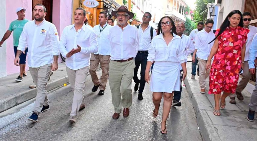 Hombres y mujeres, vestidos de blanco, caminando por calles de Cartagena, en el centro histórico.