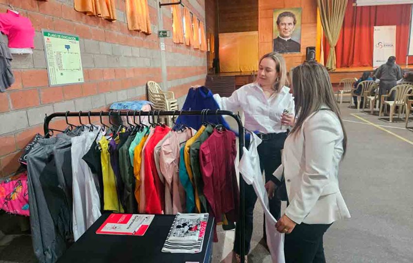 Dos mujeres observando prendas de vestir colgadas en ganchos.