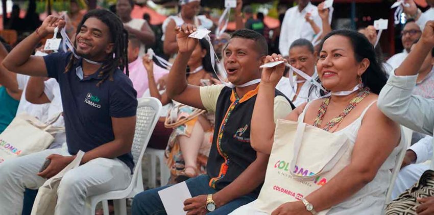 Descripción de la imagen: Hombres y mujeres sentados en silla y mirando al frente, celebrando graduación.