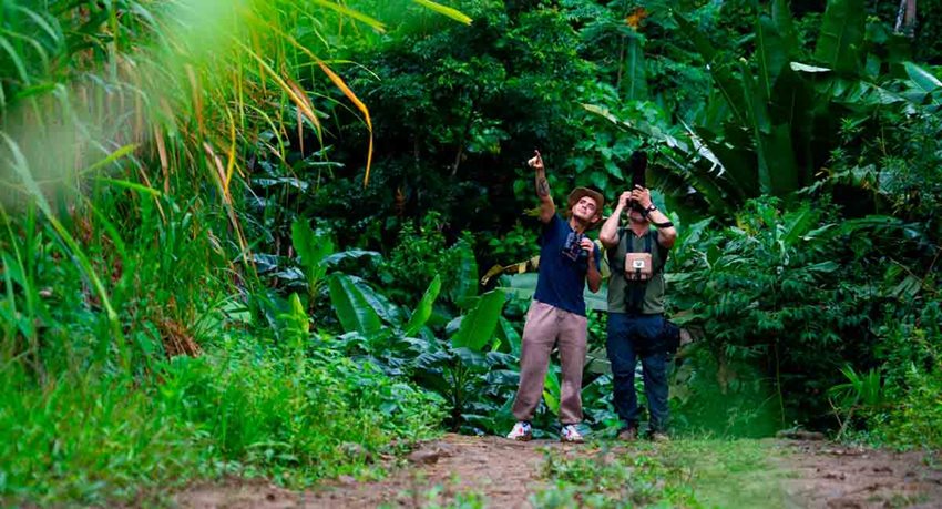 Descripción de la imagen: Dos hombres observando al cielo por medio de binoculares, en medio del campo.