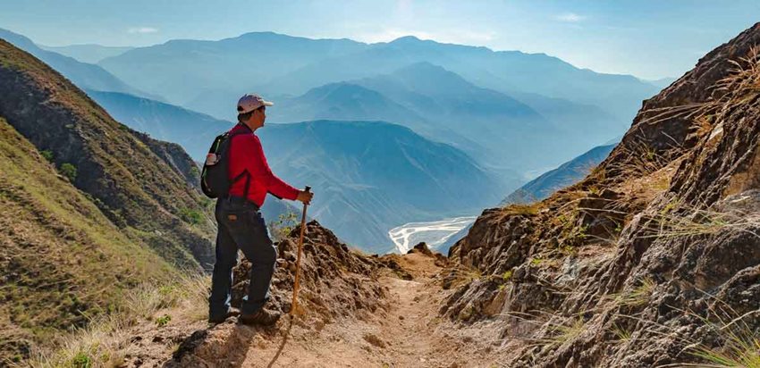 Hombre caminando por las montañas y observando el paisaje.
