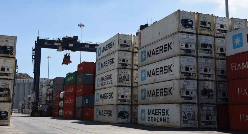 Contenedores blancos y de colores descargados en calle de puerto.