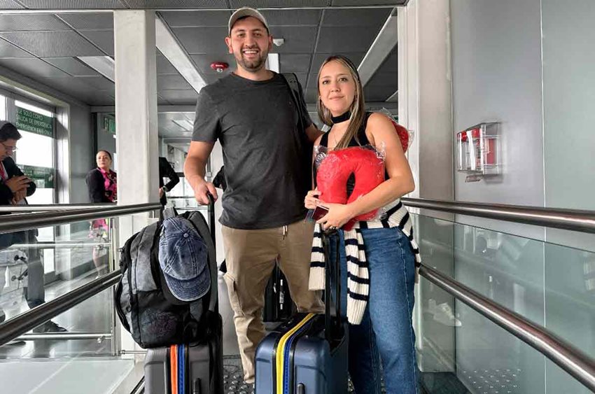 Hombre y mujer con maletas de ruedas posando para la foto en el aeropuerto.