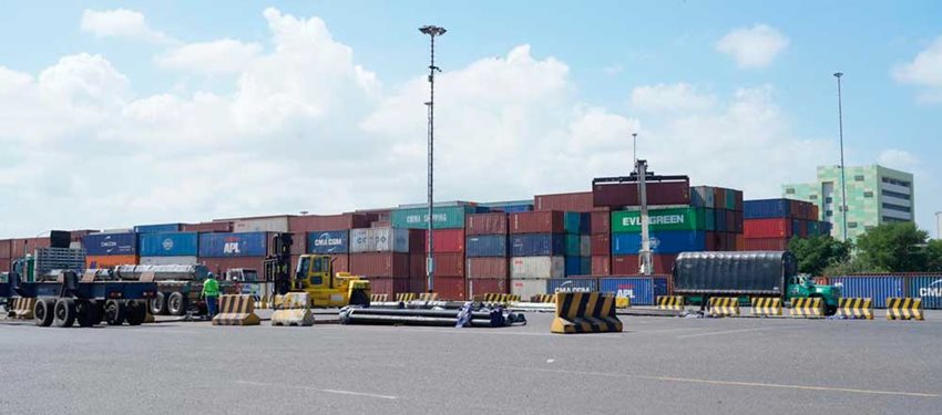 Fotografía de contenedores de colores descargados, junto a un camión.