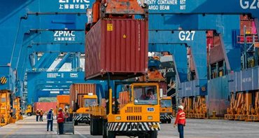 Camiones amarillos cargando contenedores vinotinto en medio de calle de zona franca. - Colombia cerró 2025 con exportaciones de bienes no mineros por US$26.388,9 millones, el 52,6 % del total vendido al mundo