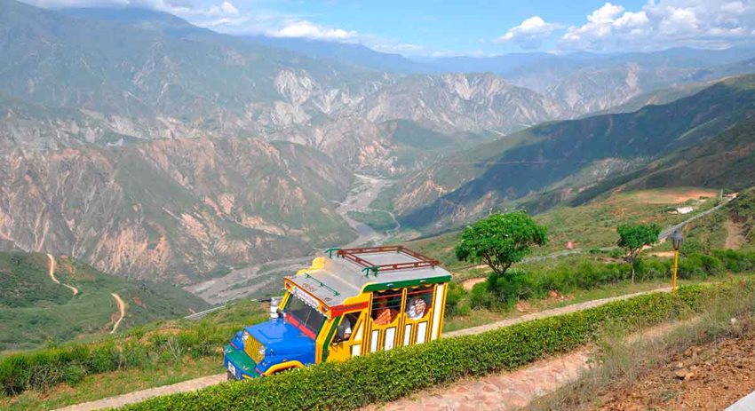 Carro de colores andando por vía en medio del Cañón del Chicamocha en Santander.