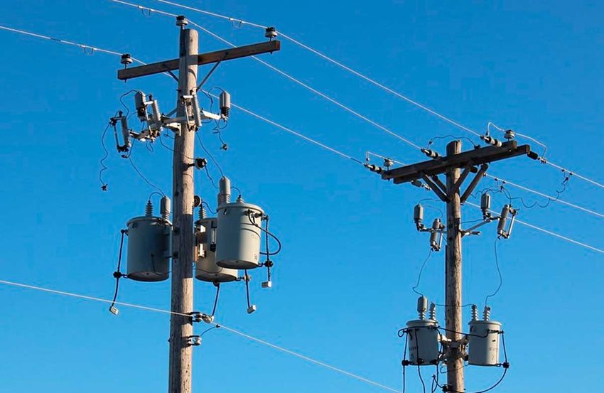 Dos postes eléctricos y cables, en medio de un cielo azul y despejado.