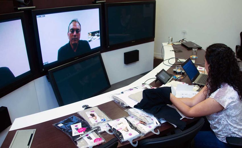 Mujer sentada con una variedad de productos textiles sobre la mesa.