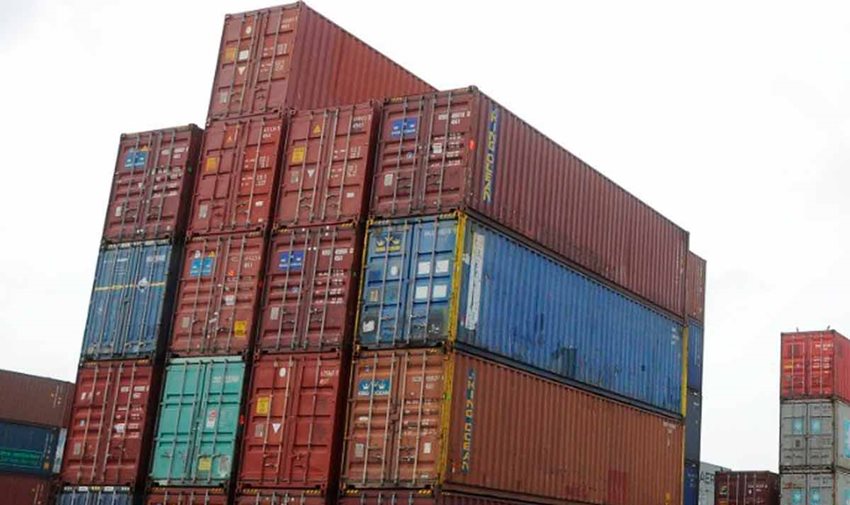 Contenedores de colores descargados y apilados en medio de calle de zona franca.