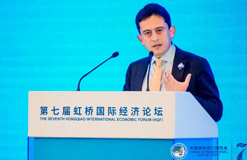 Ministro Luis Carlos Reyes vestido de traje y hablando desde un atril blanco.