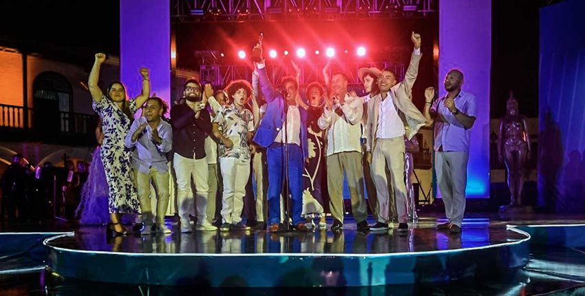 Hombres y mujeres en el escenario celebrando el recibimiento de un premio.
