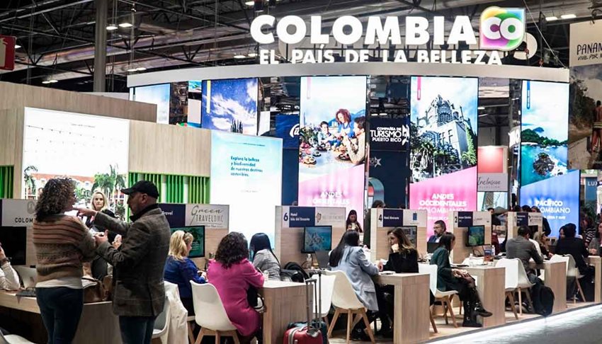 Personas en stand, sentadas en sillas y mesas haciendo negocios.