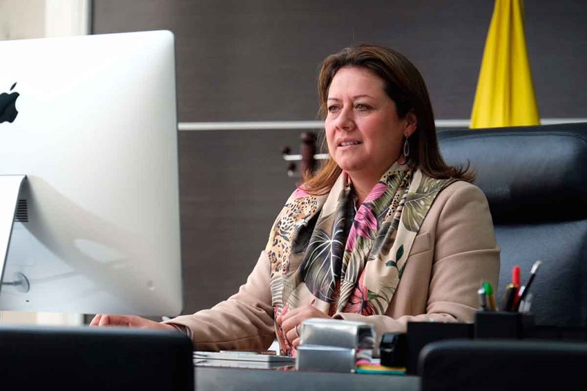 Ministra María Ximena Lombana sentada frente a su computador, usándolo, en su despacho.