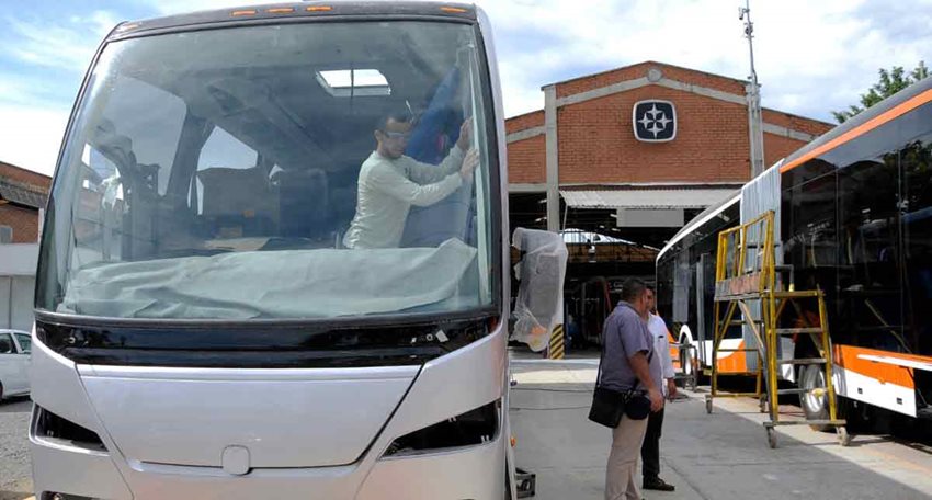 Hombre parados y trabajando en buses eléctricos blancos.