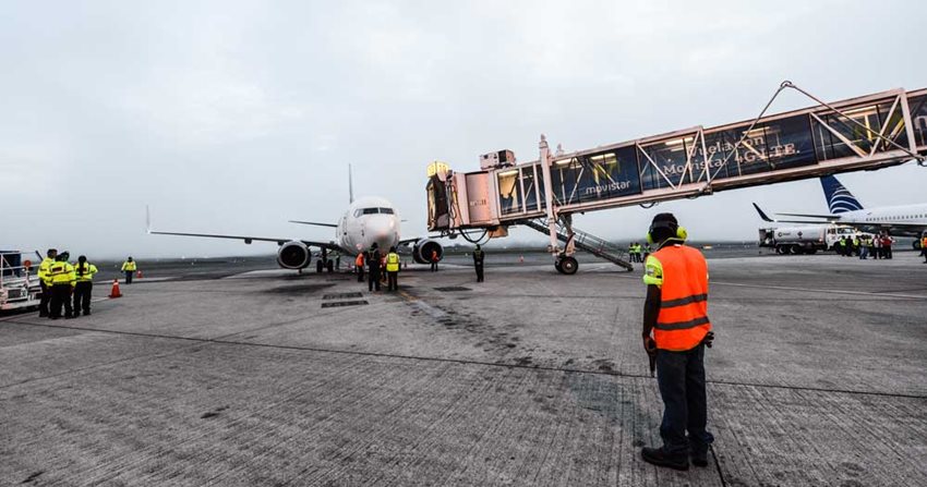 Avión parqueado en pista aérea mientras técnicos le hacen mantenimiento.