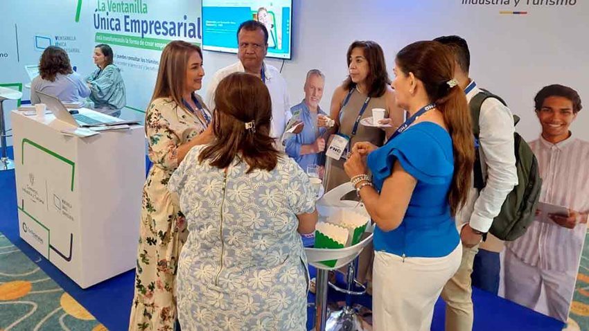 Hombres y mujeres, de pie, reunidas dialogando en medio de un evento.