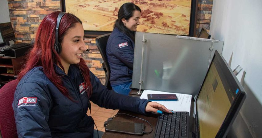 Dos mujeres sentadas trabajando en computadores. 