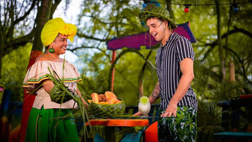Descripción de la imagen: Hombre visitando mesa de mujer que está vendiendo bebidas.