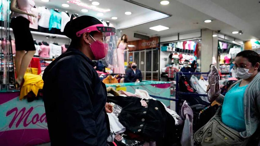 Mujeres haciendo negocios con prendas de vestir en locales de centro comercial.