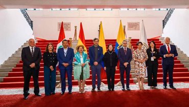 Hombres y mujeres, vestidos de traje, posando para la foto de pie, sobre tapete rojo, y con banderas de fondo. - Con balance positivo, Colombia entrega la presidencia pro tempore de la Comunidad Andina a Ecuador 