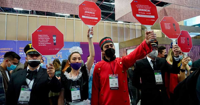 Personas disfrazadas sosteniendo letreros rojos que invitan a denunciar actos de explotación sexual.