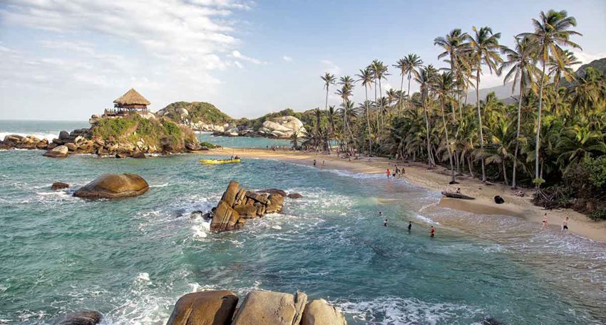 Panorámica del Parque Nacional Natural Tayrona, con personas en la playa y en el mar.