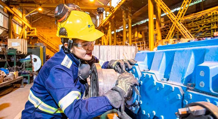 Mujer con equipo de seguridad operando una máquina.