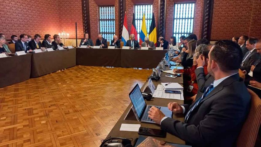 Personas sentadas en mesa redonda en medio de una reunión.