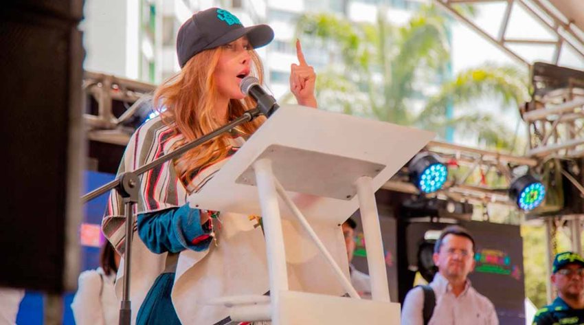 Descripción: Ministra Diana Morales hablando al público por micrófono desde atril en una tarima.