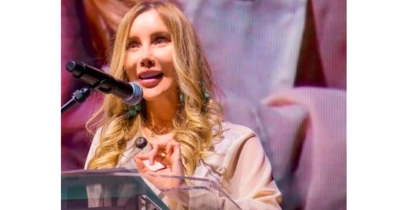 Descripción: Ministra Diana Morales hablando por micrófono, en atril, desde el escenario.