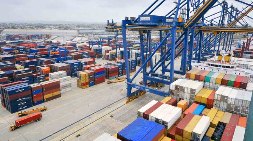 Foto panorámica de zona franca, con contenedores de colores, maquinaria y camiones.