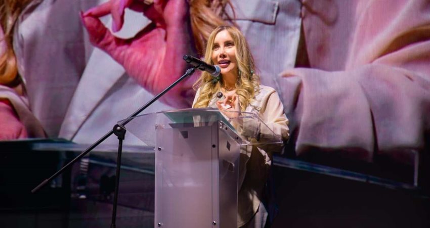 Descripción: Ministra Diana Morales hablando por micrófono al público, desde atril en el escenario.