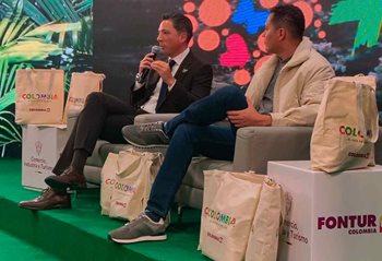 Dos hombres, sentados en sillas en el escenario, hablándole al público. MinCIT-lanzo-el-programa-Turismo-PRO-para-el-fortalecimiento-de-la-productividad-y-sostenibilidad-del-sector.jpg