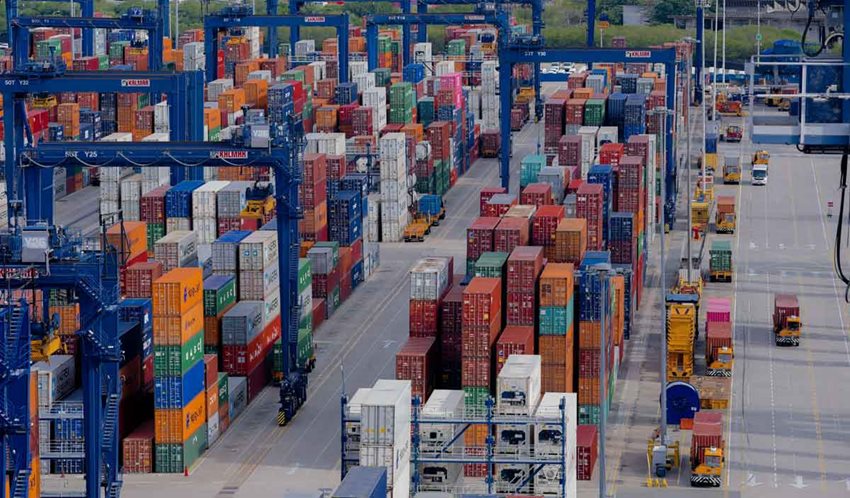 Puerto con estructuras azules y contenedores de colores descargados.