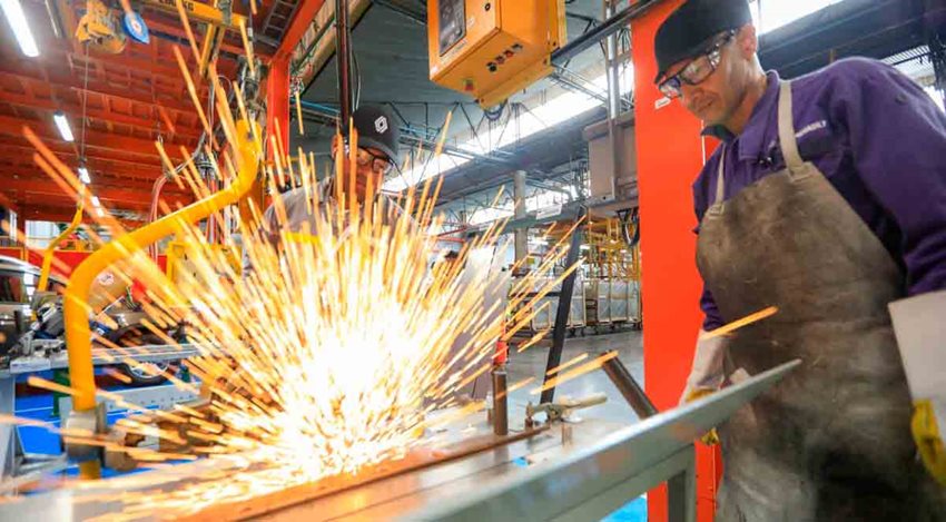 Dos hombres, con elementos de seguridad, observando el corte de una lámina de metal.