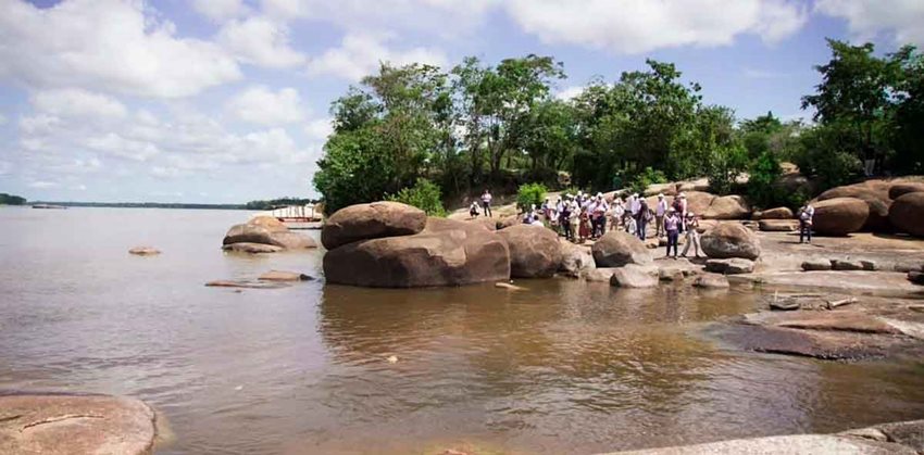 Personas de pie en rocas ubicadas en medio del río.