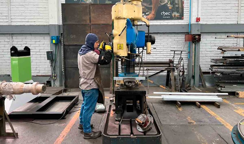 Hombre, con elementos de seguridad, operando máquina industrial en taller.