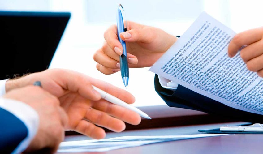 Manos de mujer y hombre sosteniendo documentos y bolígrafos.