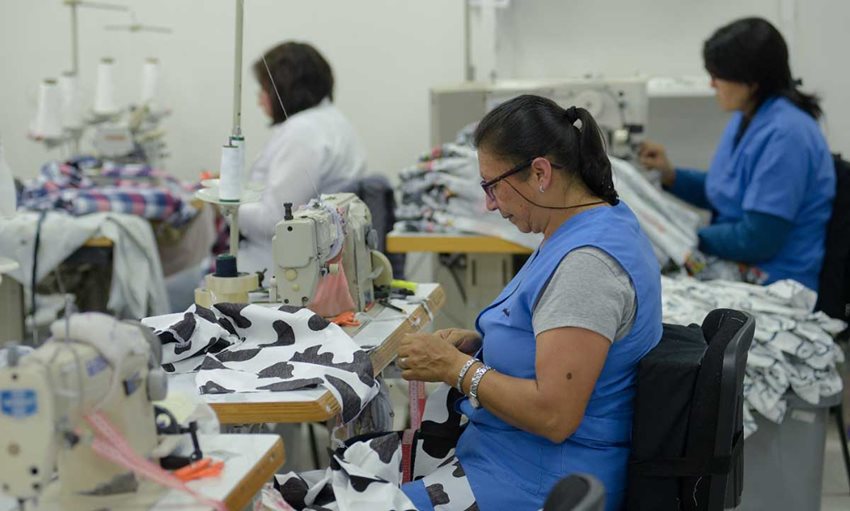 Mujeres cosiendo enfrente de sus máquinas de coser.