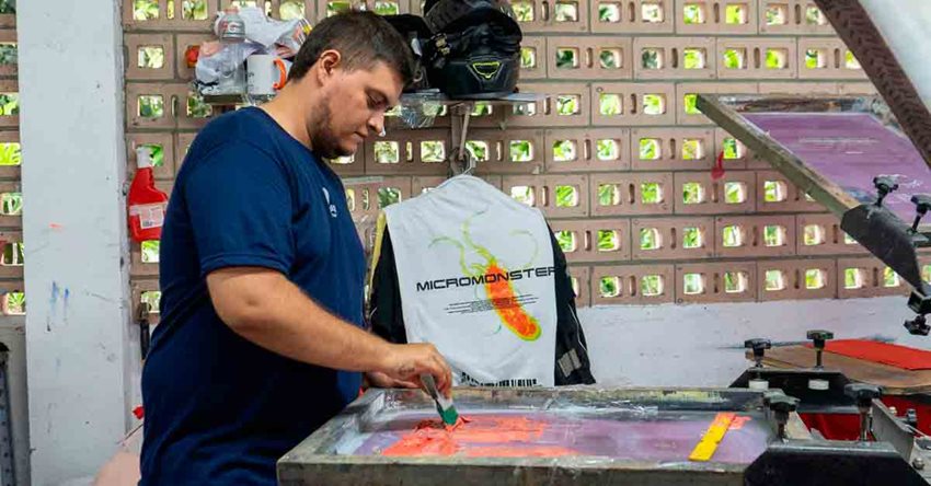 Hombre de camiseta azul, y de pie, trabajando con pintura en lata.