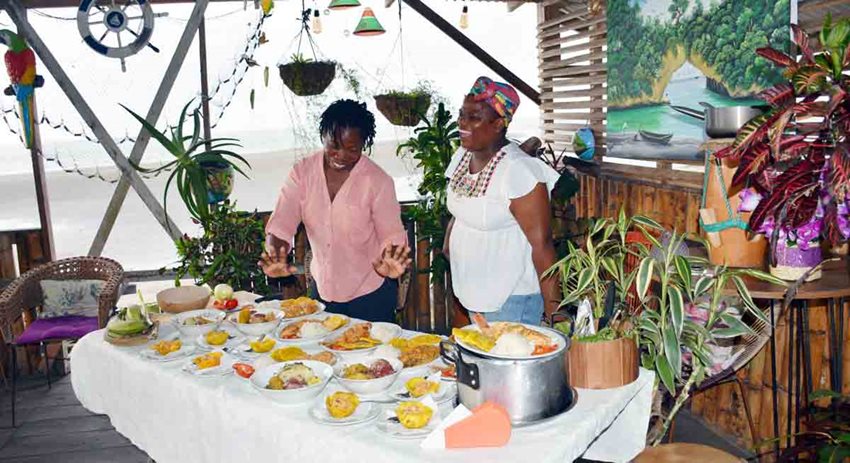 Dos mujeres de color presentando las comidas típicas que prepararon.