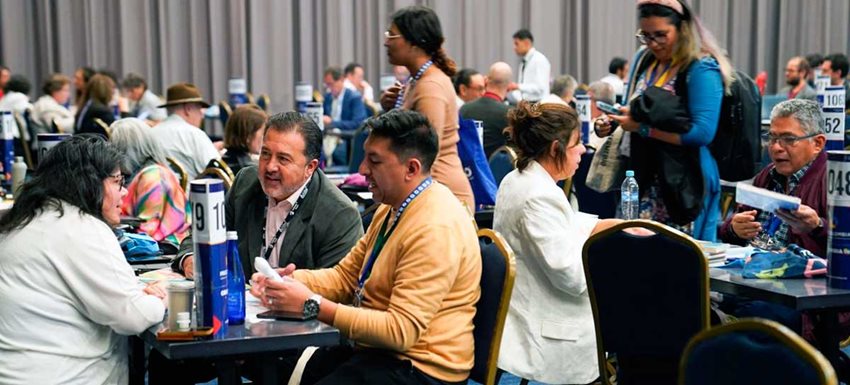 Personas reunidas en mesas, haciendo negocios.