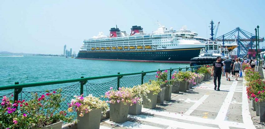 Crucero alojado en el muelle, mientras personas caminan por malecón.