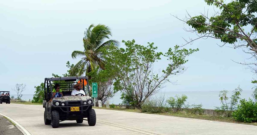 Mujer y hombre en un carrito de golf, conduciendo por la carretera vía al mar de la isla de San Andrés.